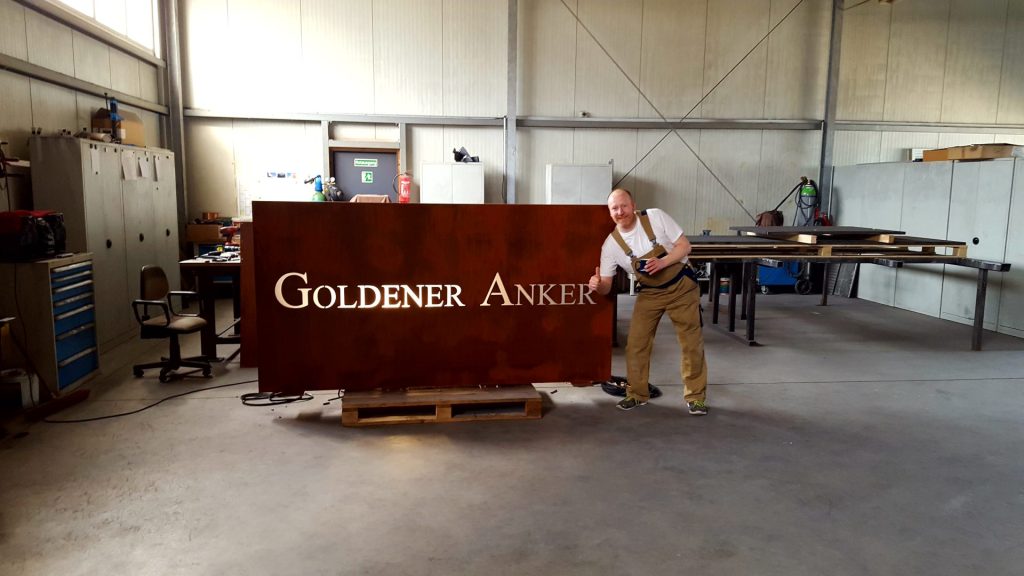 Mann neben Schildertext Goldener Anker